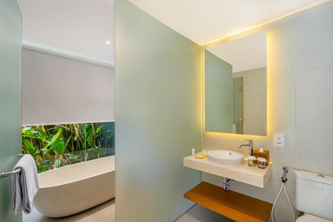 a bathroom with a sink and a tub and a mirror at Citadines Berawa Beach Bali Resort in Canggu