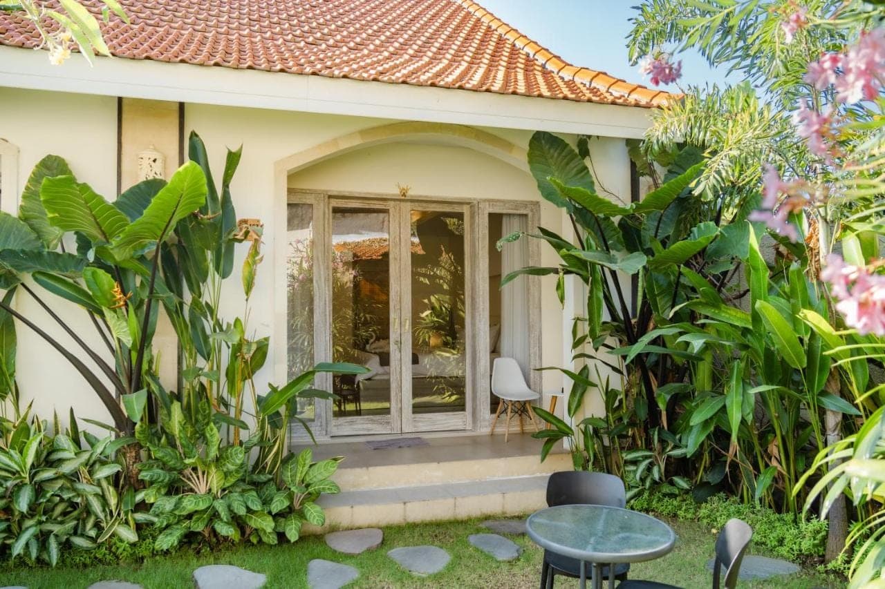 a house with a glass door in a garden at D'Leafy Seminyak in Seminyak
