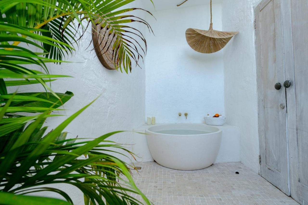 a bathroom with a bath tub in a room with plants at Gravity Boutique Suites in Uluwatu