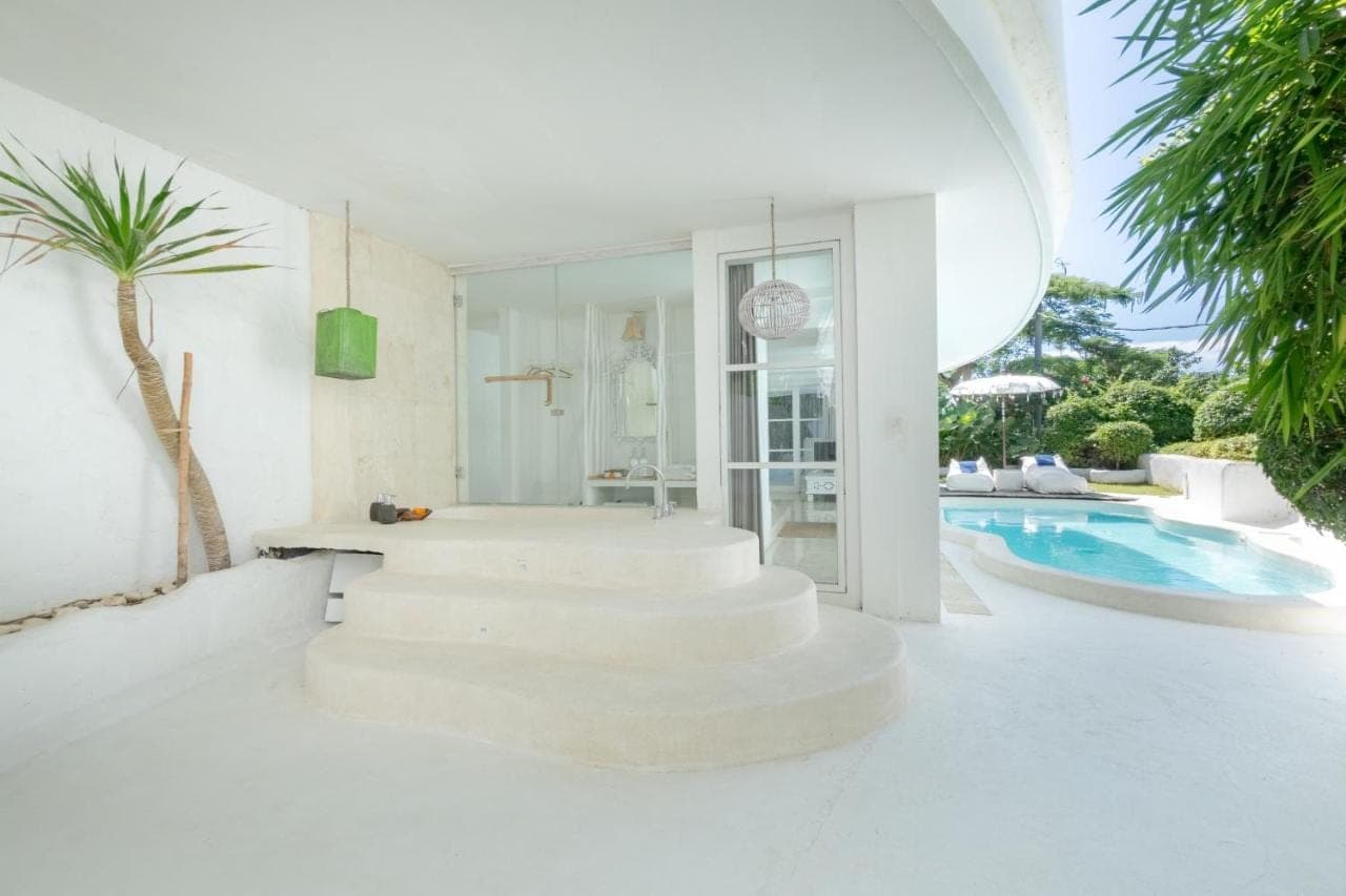 a white house with stairs next to a swimming pool at Gravity Boutique Suites in Uluwatu