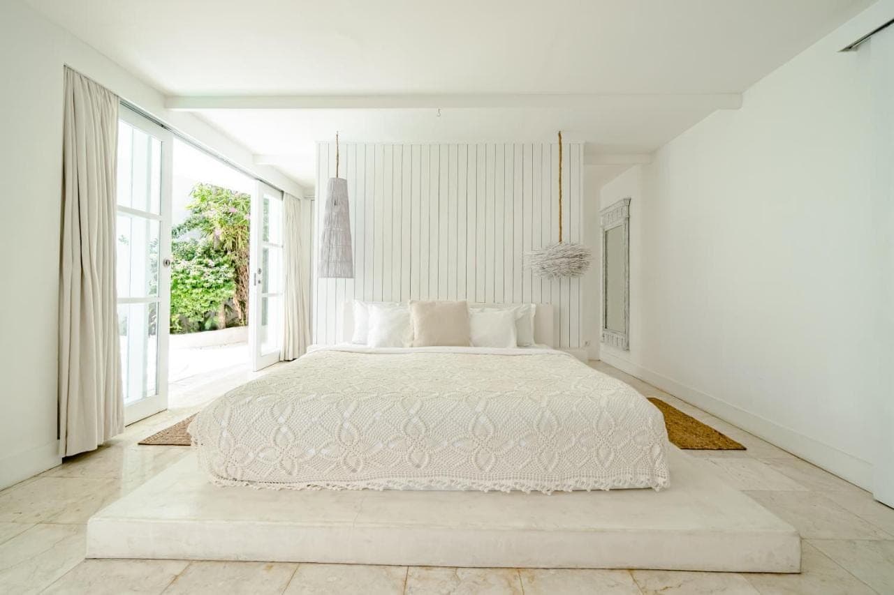 a white bedroom with a large bed and a window at Gravity Boutique Suites in Uluwatu