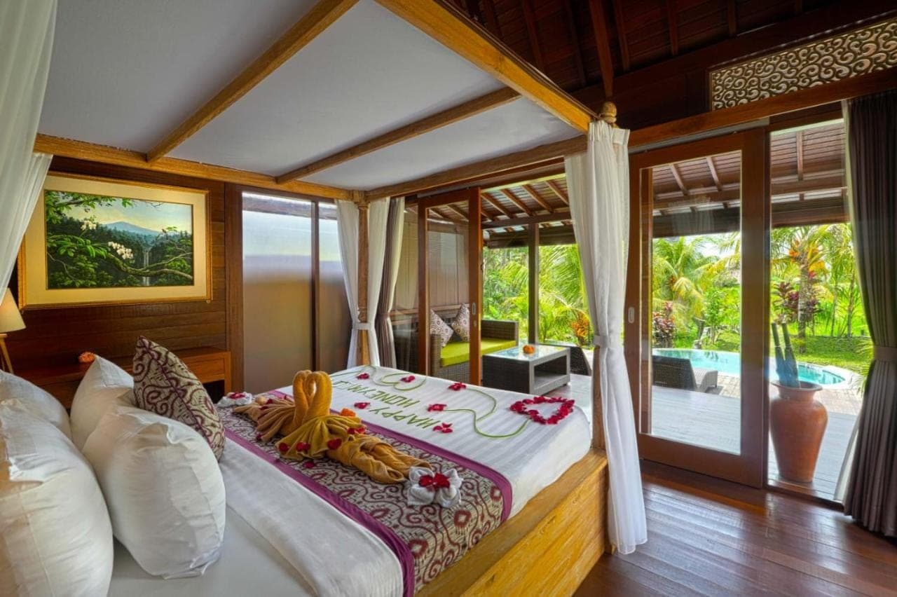 a bedroom with a bed with a view of a pool at PB Pondok Gandalangu Suite Villas Ubud Bali in Ubud
