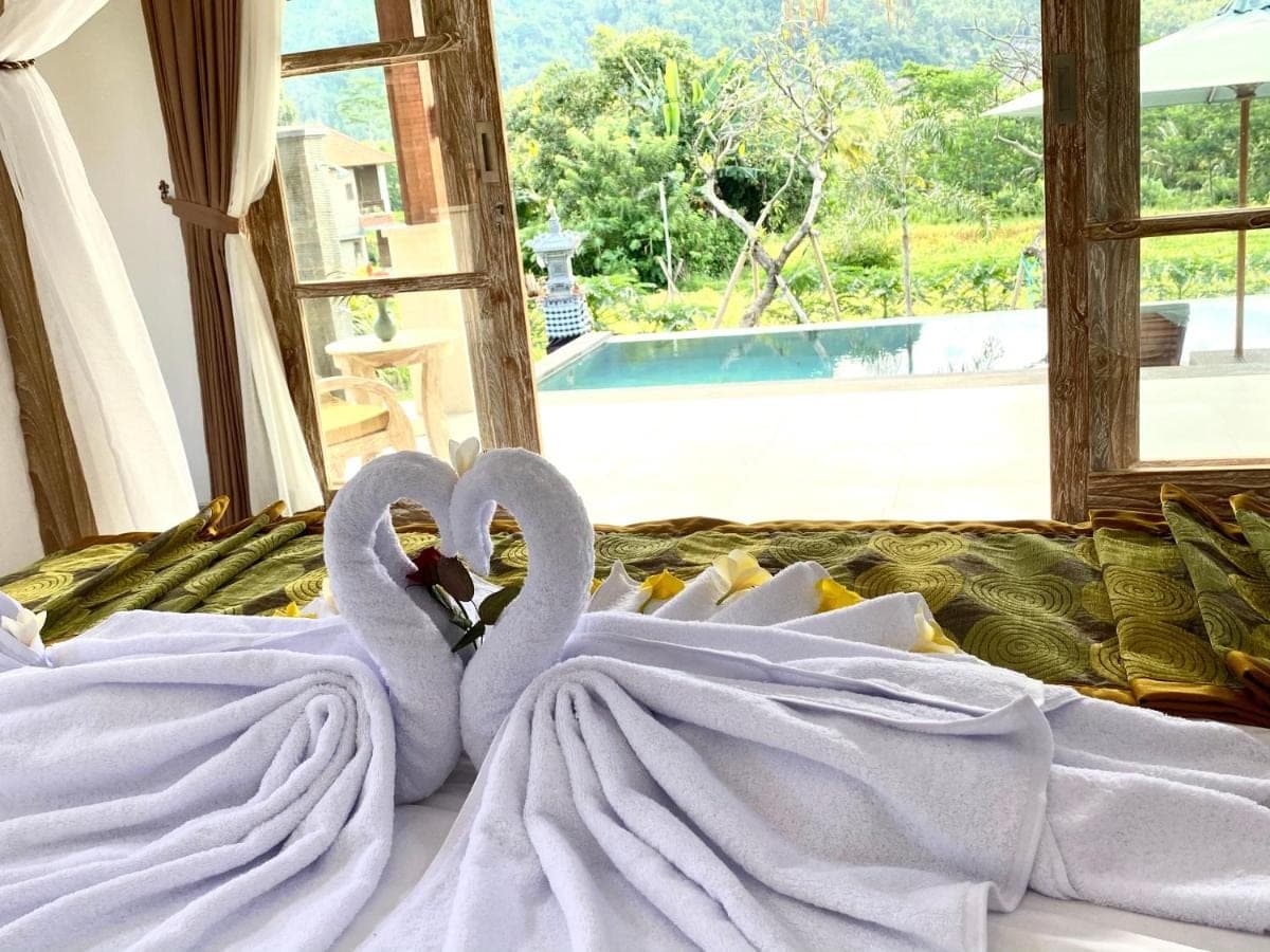 two white swans sitting on top of a bed at Alamdhari Villa Sidemen in Sidemen
