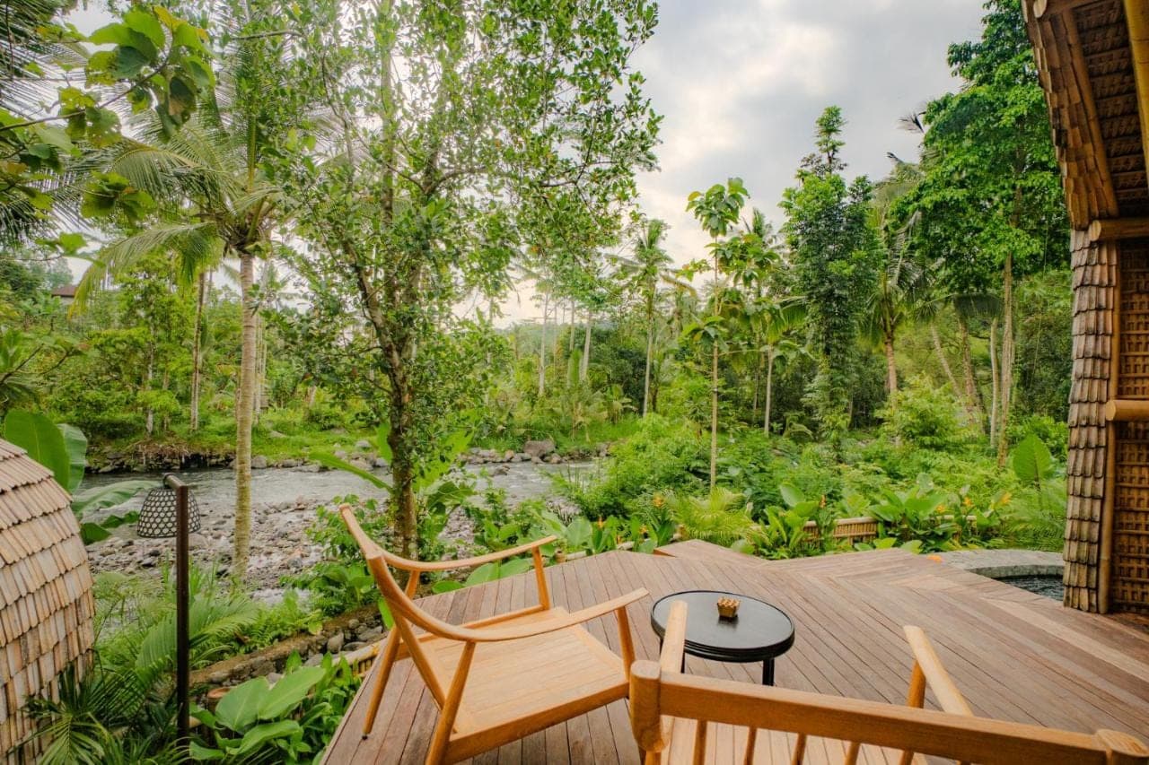 a wooden deck with two chairs and a table at Atamendra Bali Resort at Sidemen in Sidemen