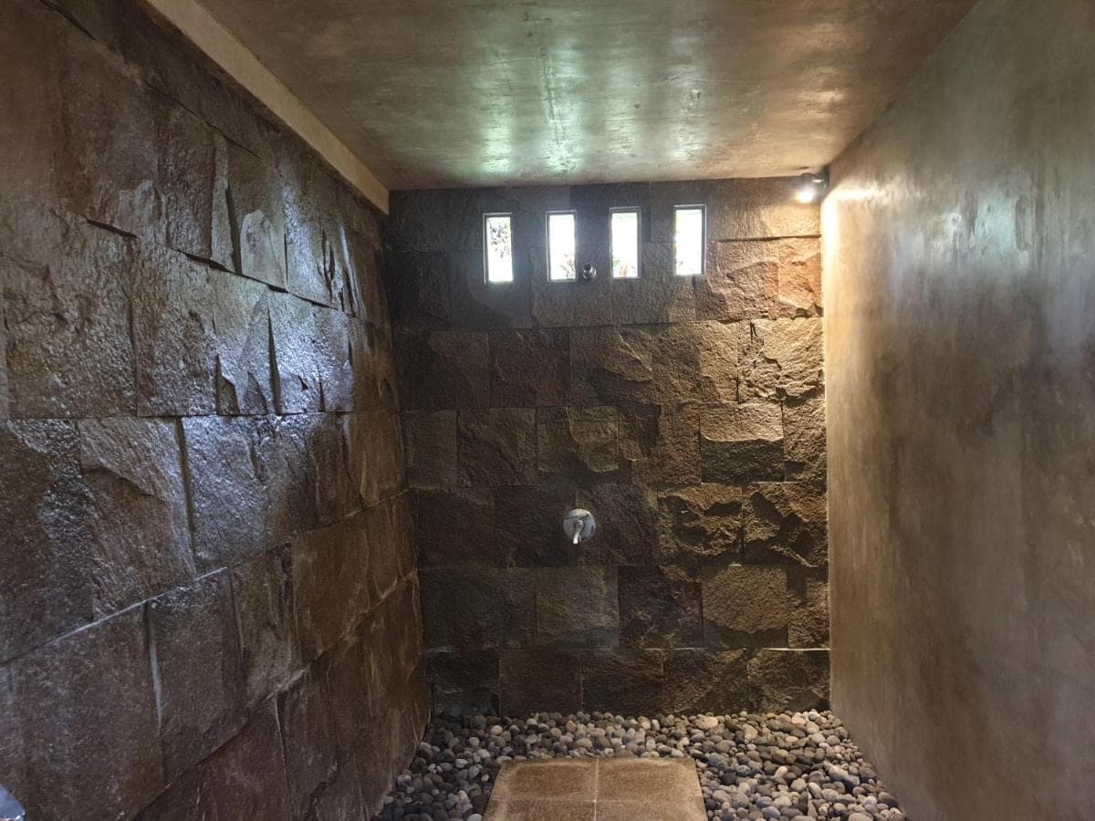 a room with a stone wall and a window at Rumah Sidemen in Sidemen