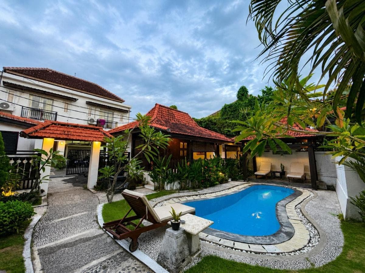a backyard with a swimming pool and a house at Surfer Paradise Villas Bali in Canggu