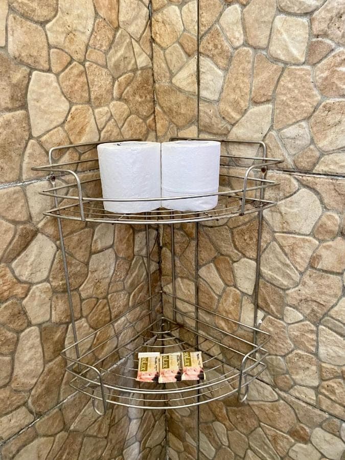 a shelf with towels on a stone wall at Frog Homestay Sanur in Sanur