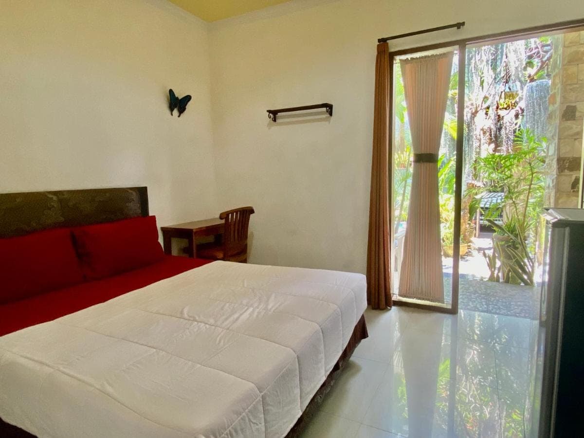 a bedroom with a bed and a large window at Frog Homestay Sanur in Sanur