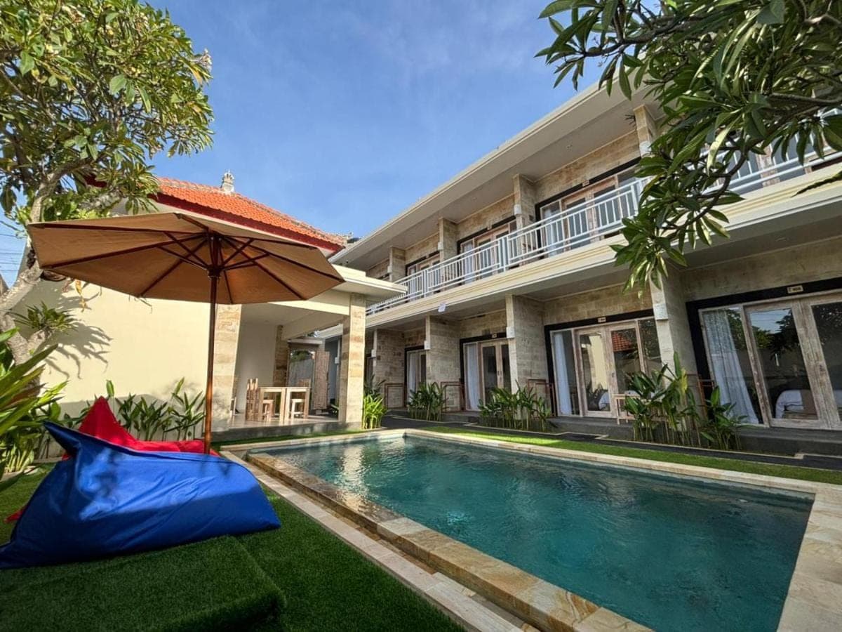a house with a swimming pool and an umbrella at Casa Benoa Homestay in Nusa Dua