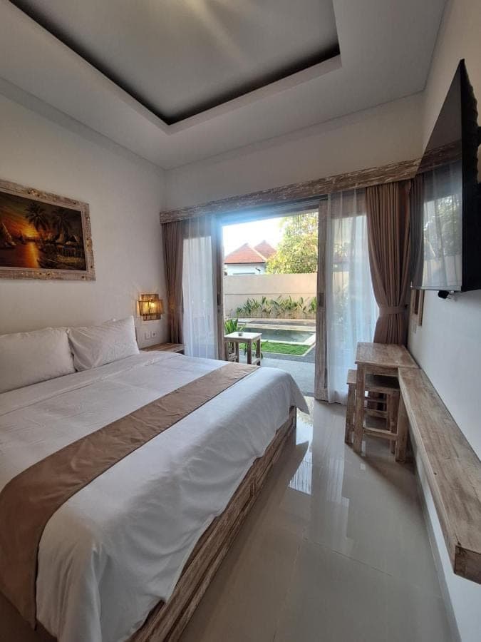 a bedroom with a large bed and a large window at Casa Benoa Homestay in Nusa Dua