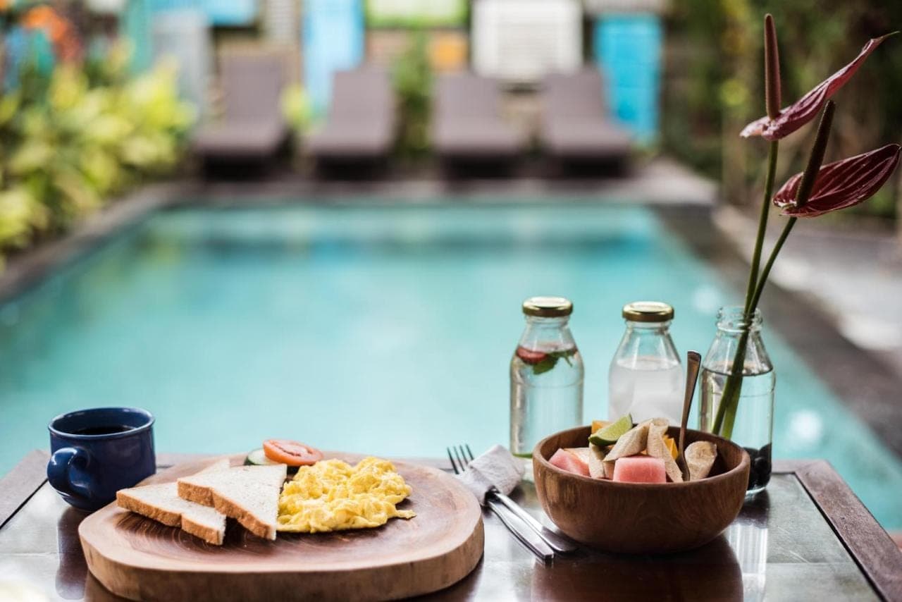 a table with a plate of food next to a pool at Arana Garden Ubud in Ubud