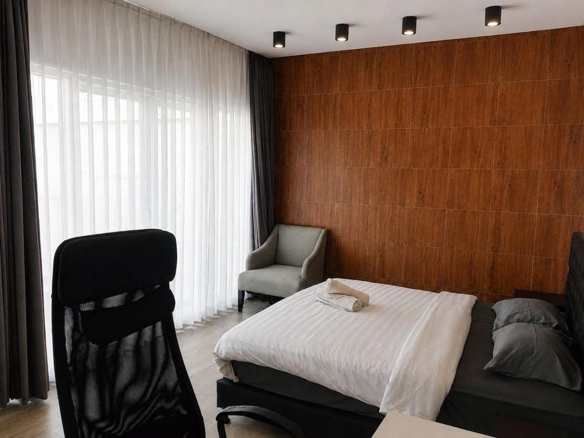 a bedroom with a bed and a chair in it at Nusa Dua Oasis Elara 2BR Private Pool Villa in Nusa Dua