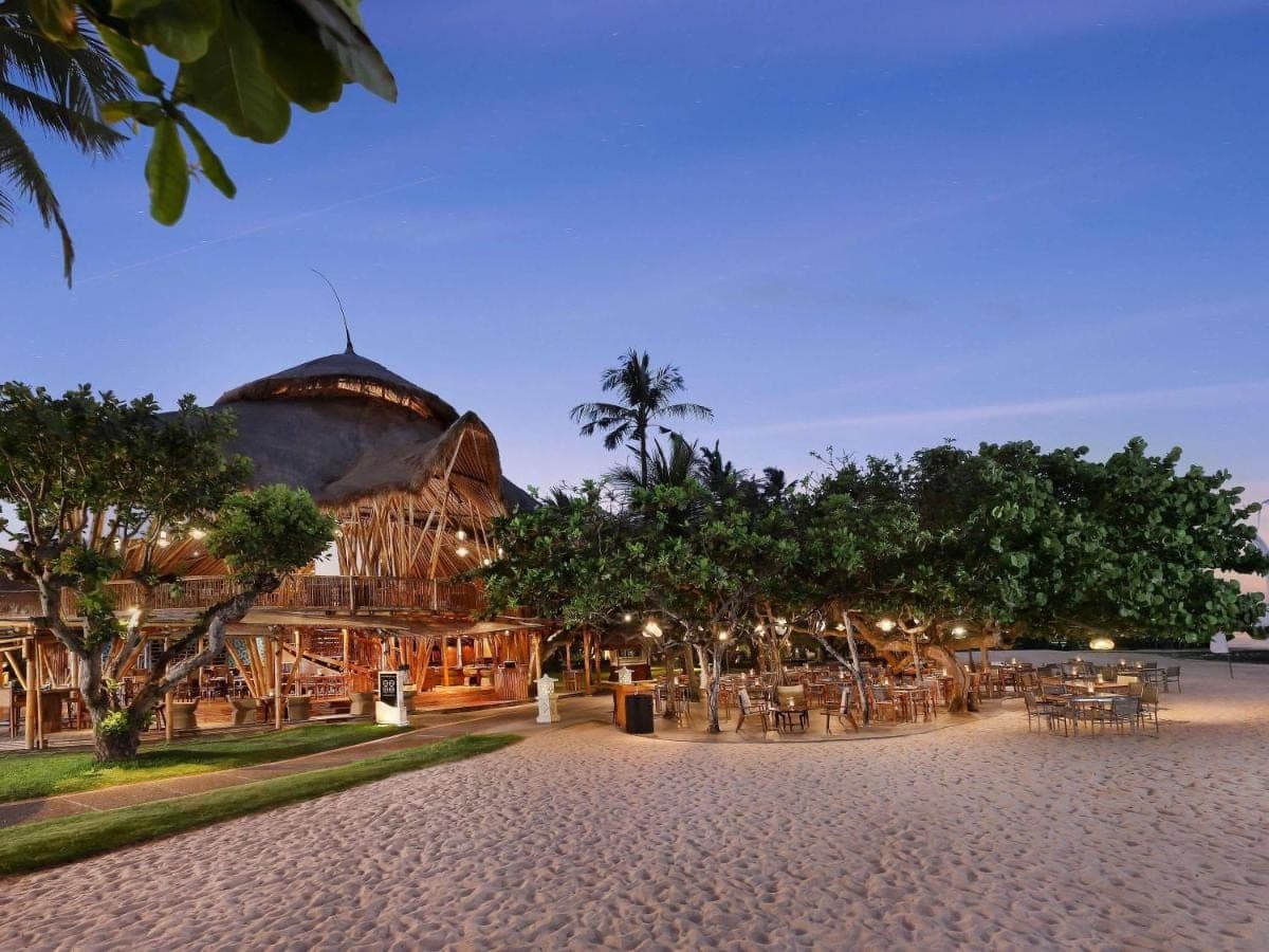 a building with tables and trees in front of it at Nusa Dua Beach Hotel and Spa - Handwritten Collection in Nusa Dua