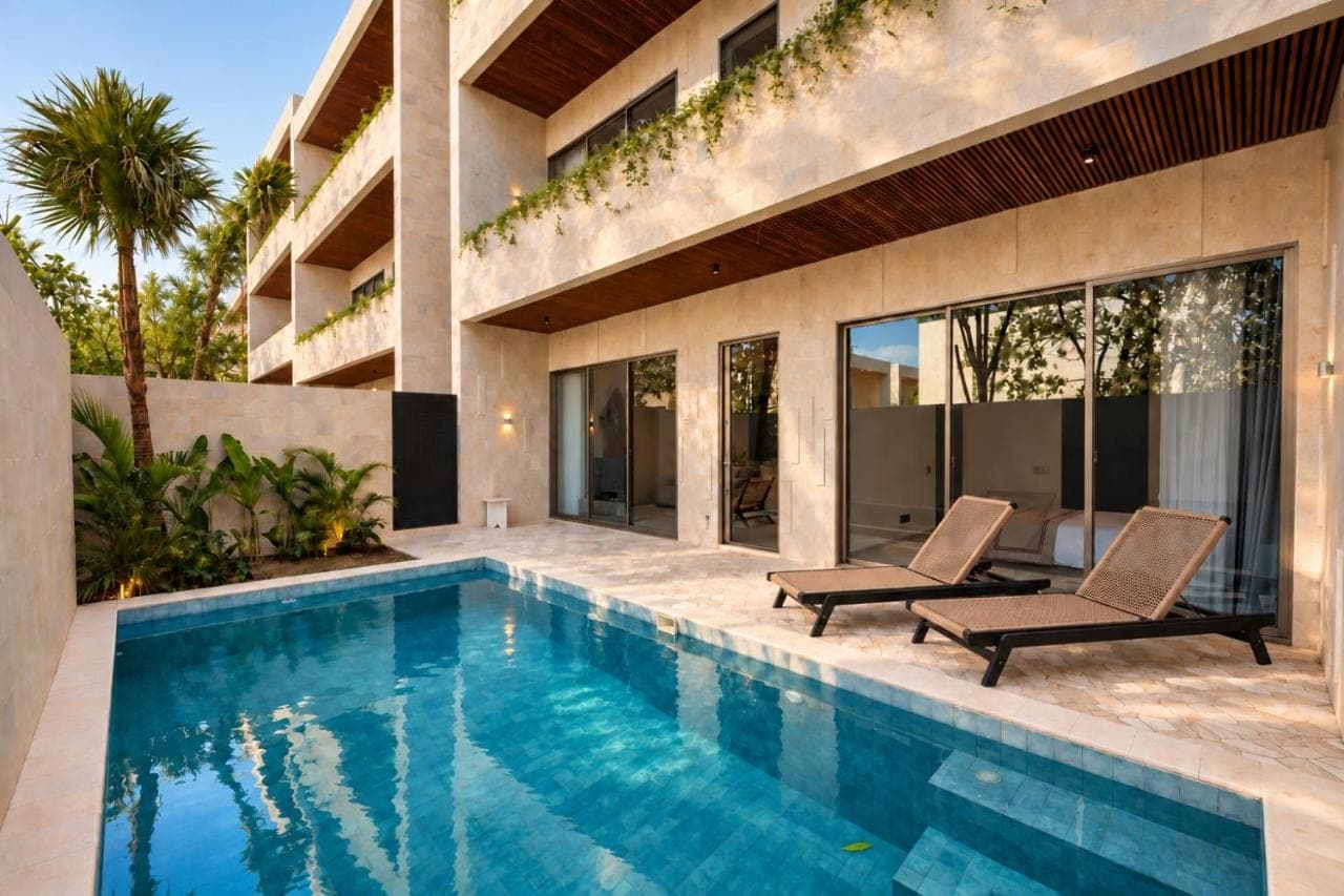 a house with a swimming pool and two chairs next to it at Surfside Uluwatu Resort in Uluwatu