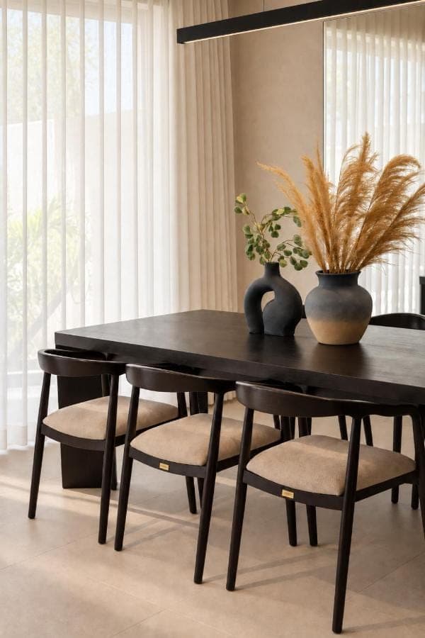 a black dining room table and chairs with a plant at Surfside Uluwatu Resort in Uluwatu