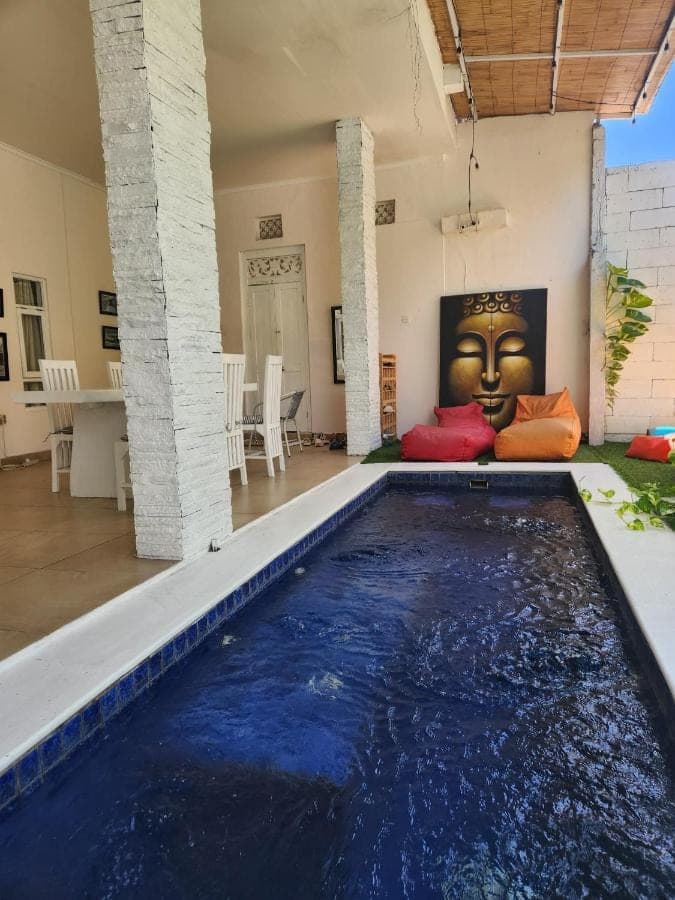 a swimming pool in a living room with a face on the wall at Capricorn Villa in Seminyak