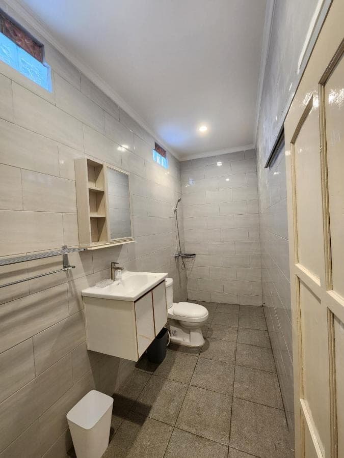 a white bathroom with a toilet and a sink at Capricorn Villa in Seminyak