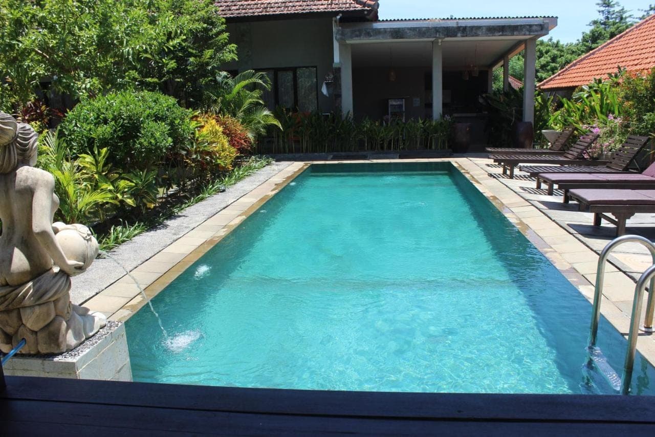 a swimming pool in front of a house at Paranyogan Homestay in Uluwatu