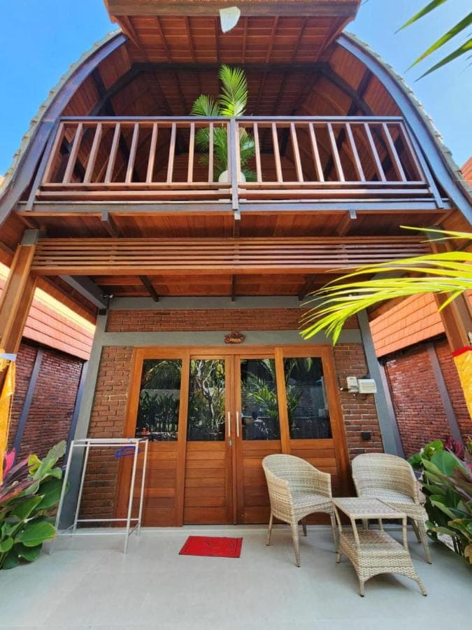 a house with a wooden door and two chairs at Pondok Kembar Homestay in Uluwatu