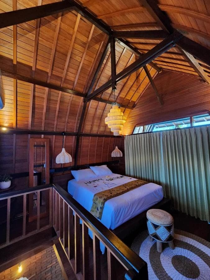 a bedroom with a bed in a wooden room at Pondok Kembar Homestay in Uluwatu