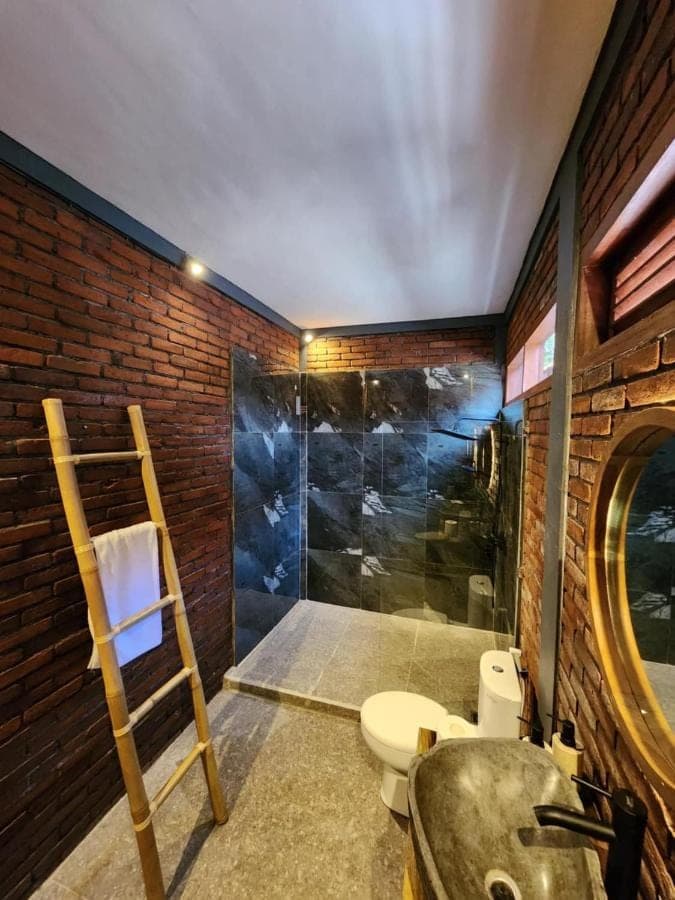 a bathroom with a shower and a toilet and a sink at Pondok Kembar Homestay in Uluwatu