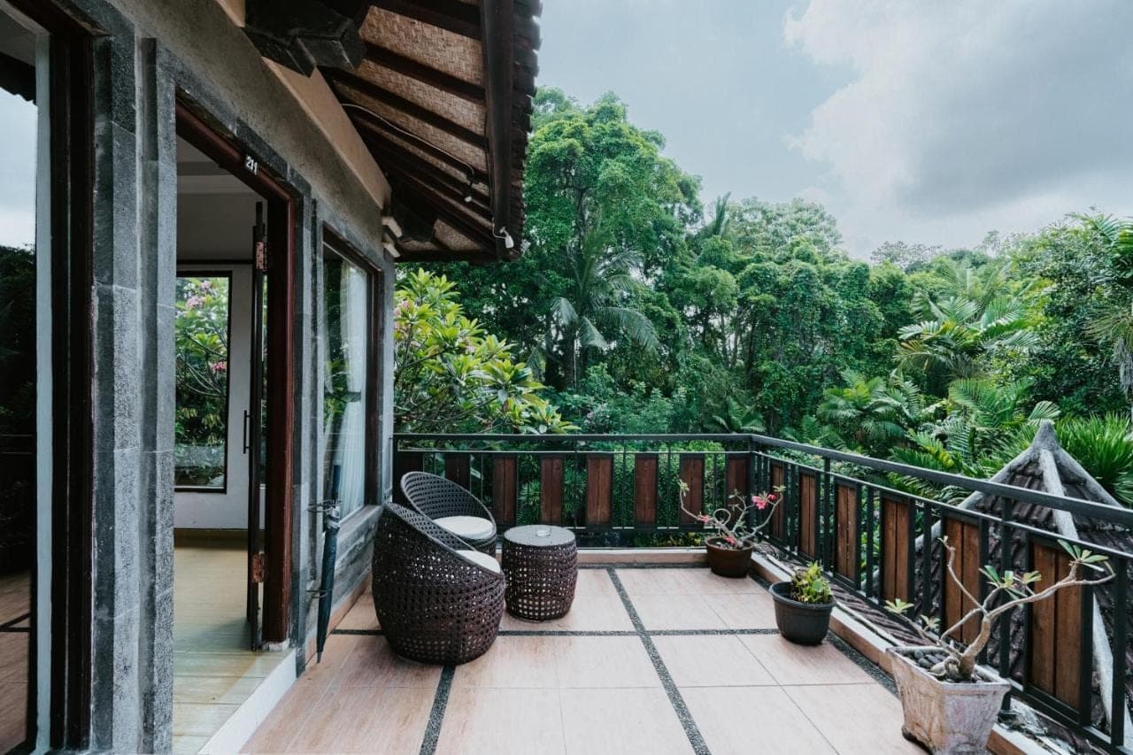 a balcony with a view of the forest at Dewangga Ubud in Ubud