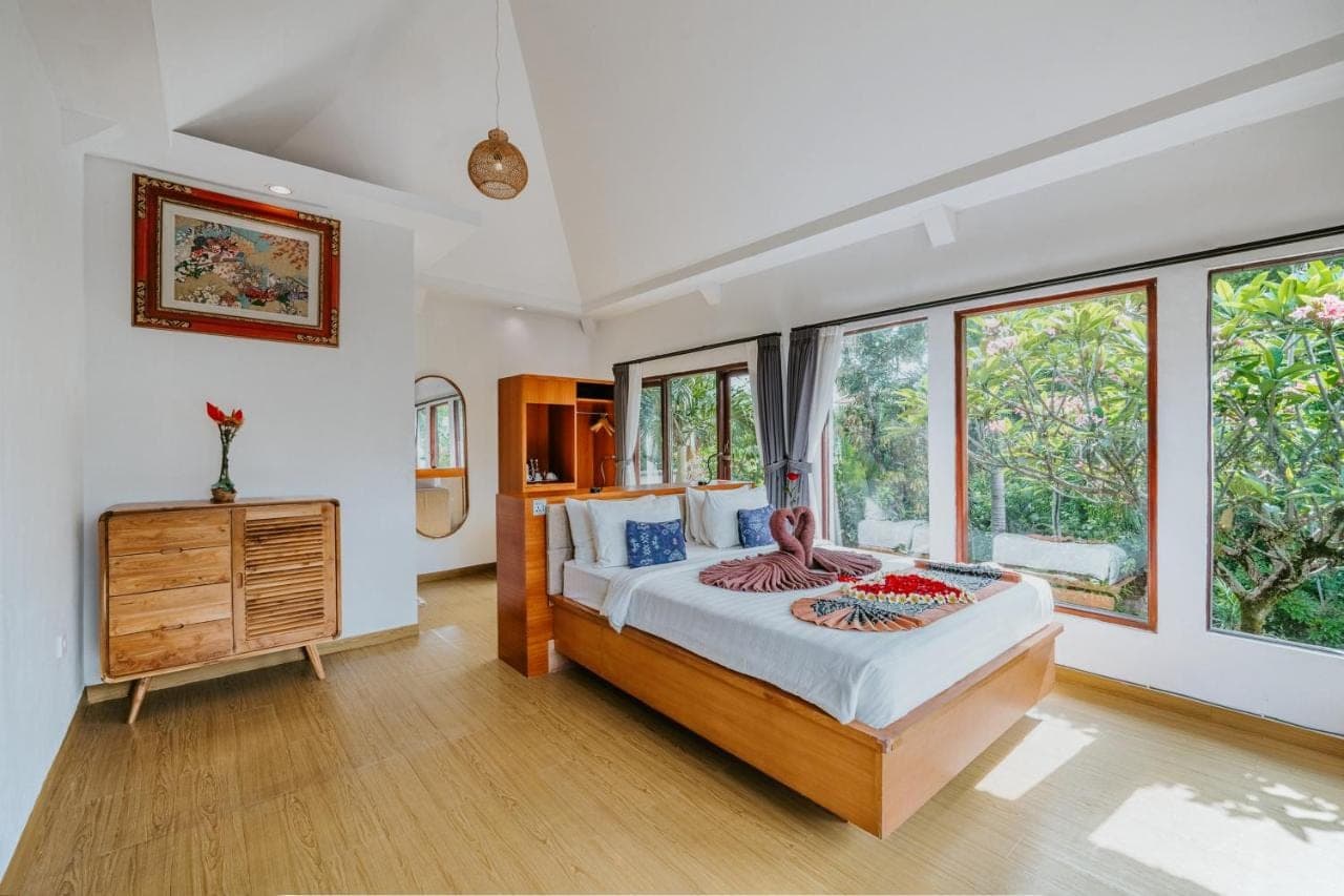 a bedroom with a bed and some windows at Dewangga Ubud in Ubud