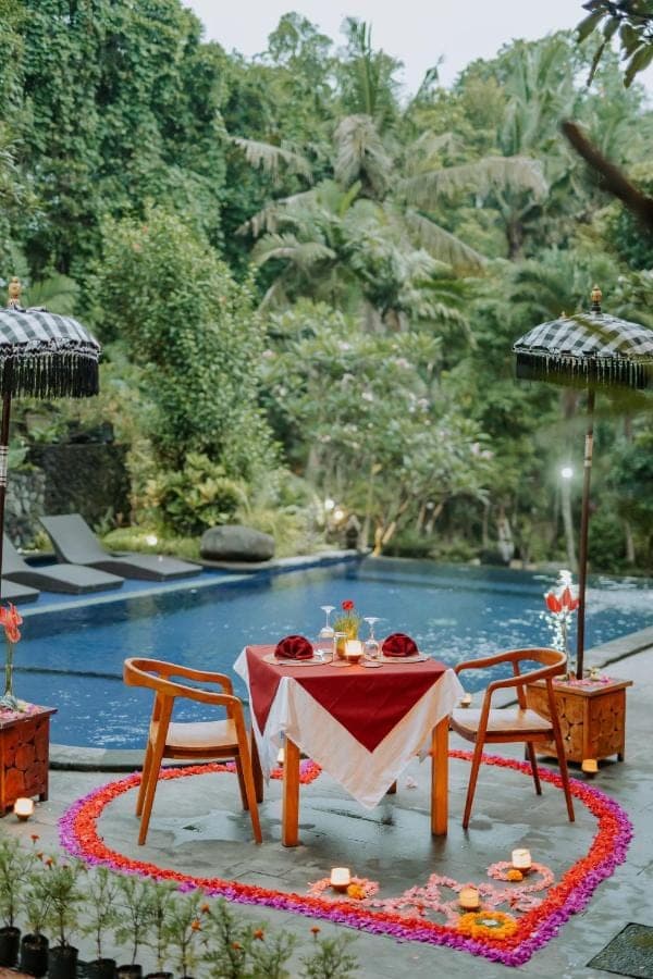 a table and two chairs and a swimming pool at Dewangga Ubud in Ubud