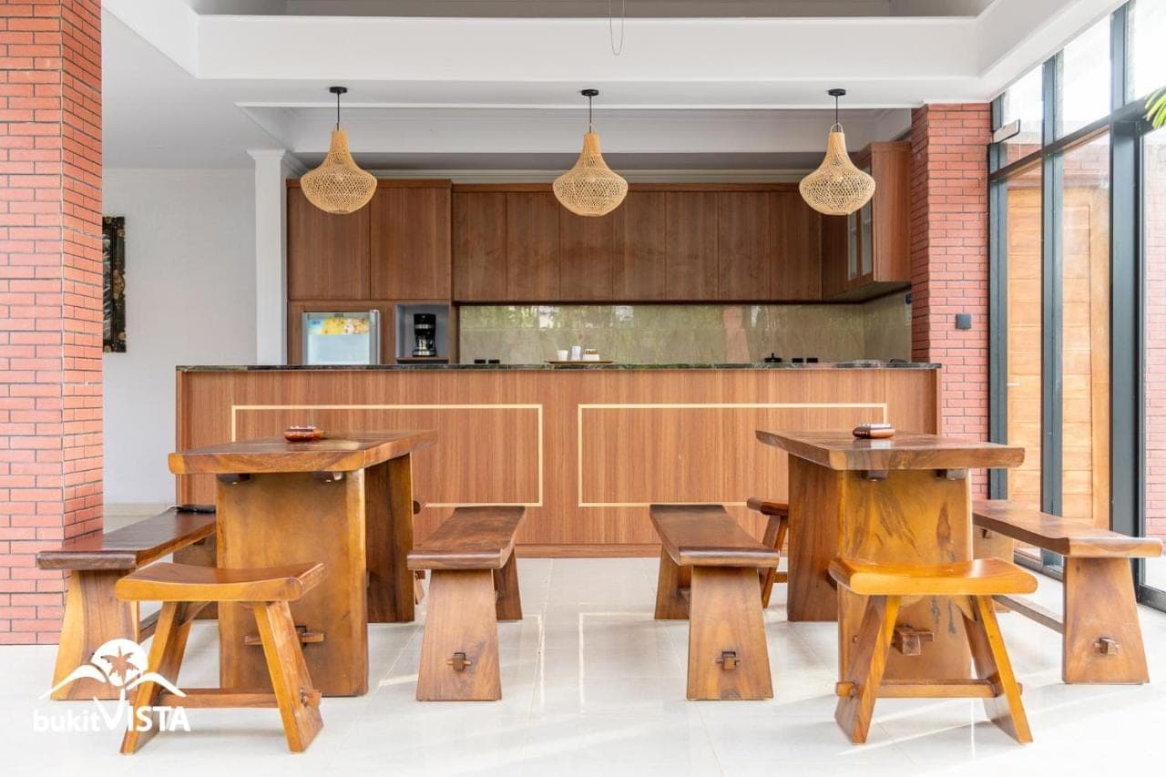 a kitchen with wooden tables and wooden chairs at The Pandawa Bali by Bukit Vista in Nusa Dua