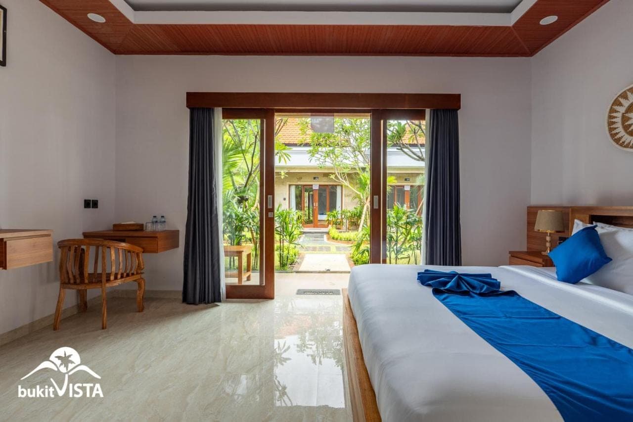 a bedroom with a bed and a desk and a window at The Pandawa Bali by Bukit Vista in Nusa Dua