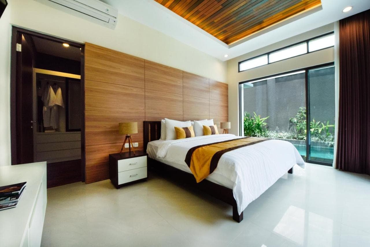 a bedroom with a large bed and a large window at La Paradis Villa in Canggu