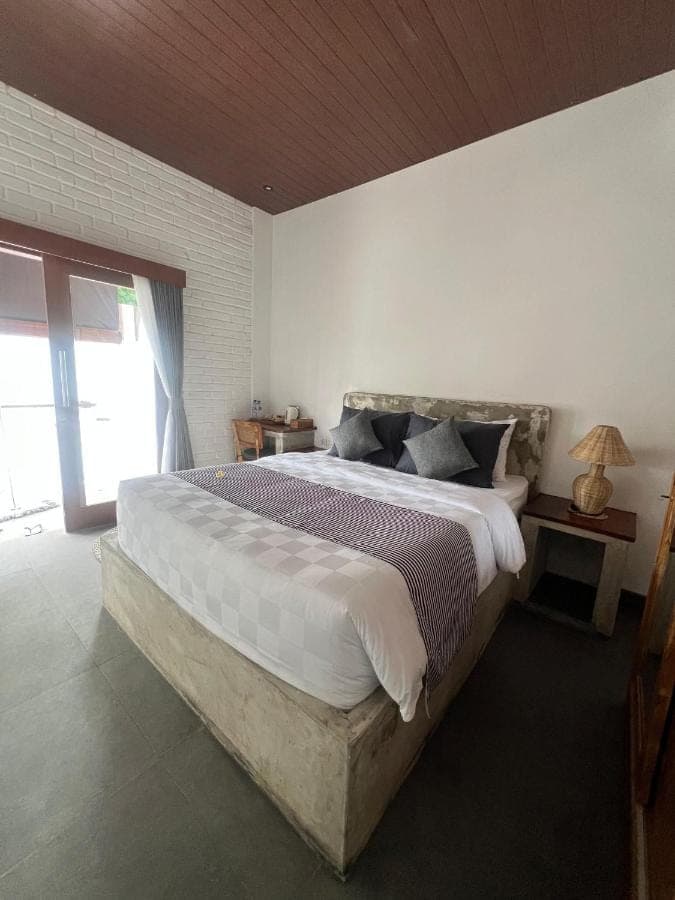 a bedroom with a large bed and a window at Ishana House Padang-Padang in Uluwatu