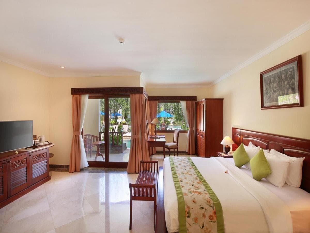 a bedroom with a large bed and a television at The Grand Bali Nusa Dua in Nusa Dua