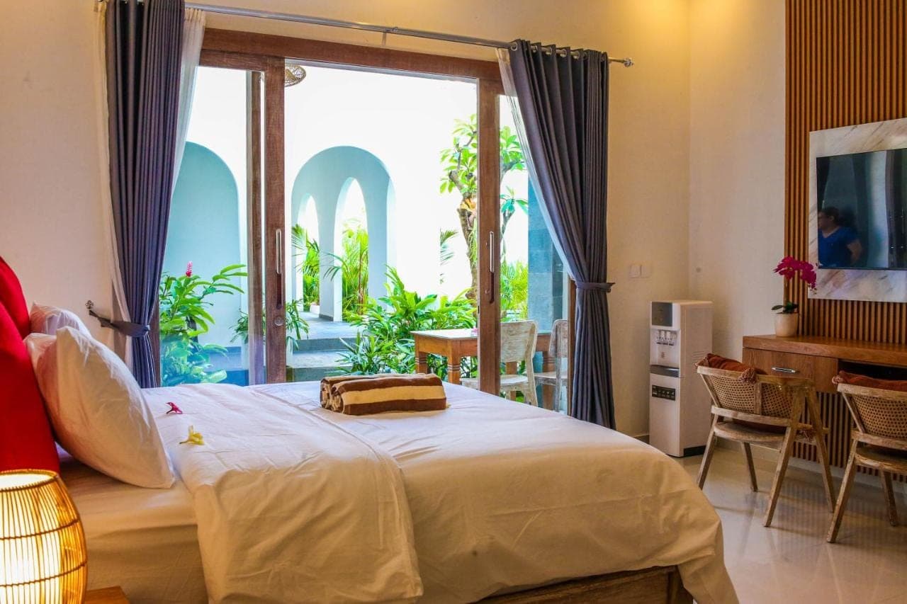 a bedroom with a bed and a large window at Umi Umi Homestay Sanur in Sanur
