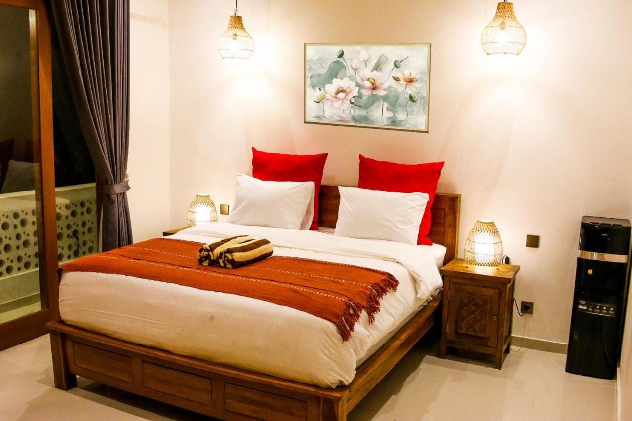 a bedroom with a large bed with red pillows at Umi Umi Homestay Sanur in Sanur