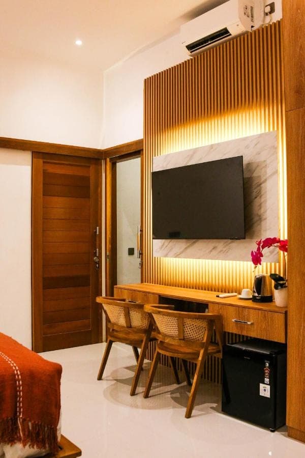 a living room with a desk with a television on a wall at Umi Umi Homestay Sanur in Sanur