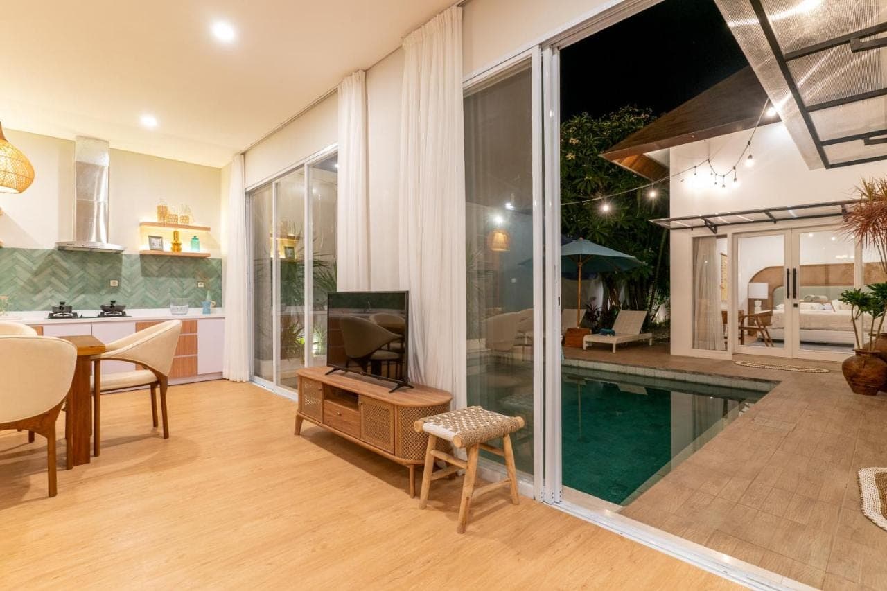 a living room with a television and a swimming pool at Villa Palma Blanca Canggu by Nagisa Bali in Canggu