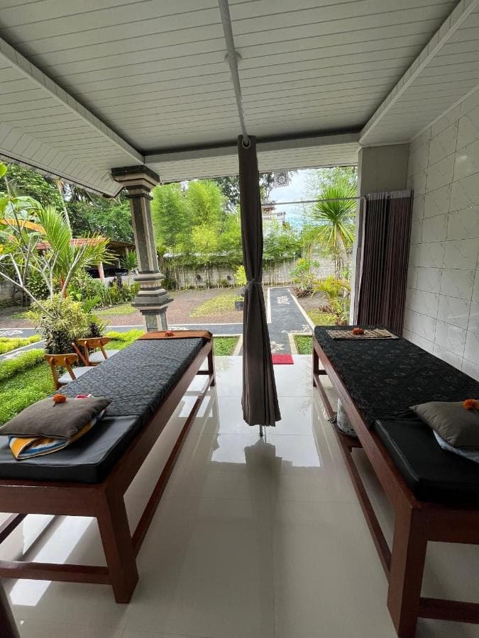 two beds in a room with a porch at Kawandini Homestay in Sidemen