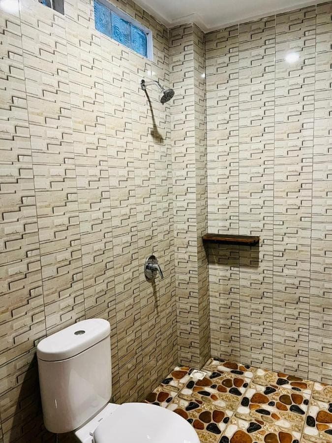 a bathroom with a toilet and a shower at Milky Way Homestay Canggu in Canggu
