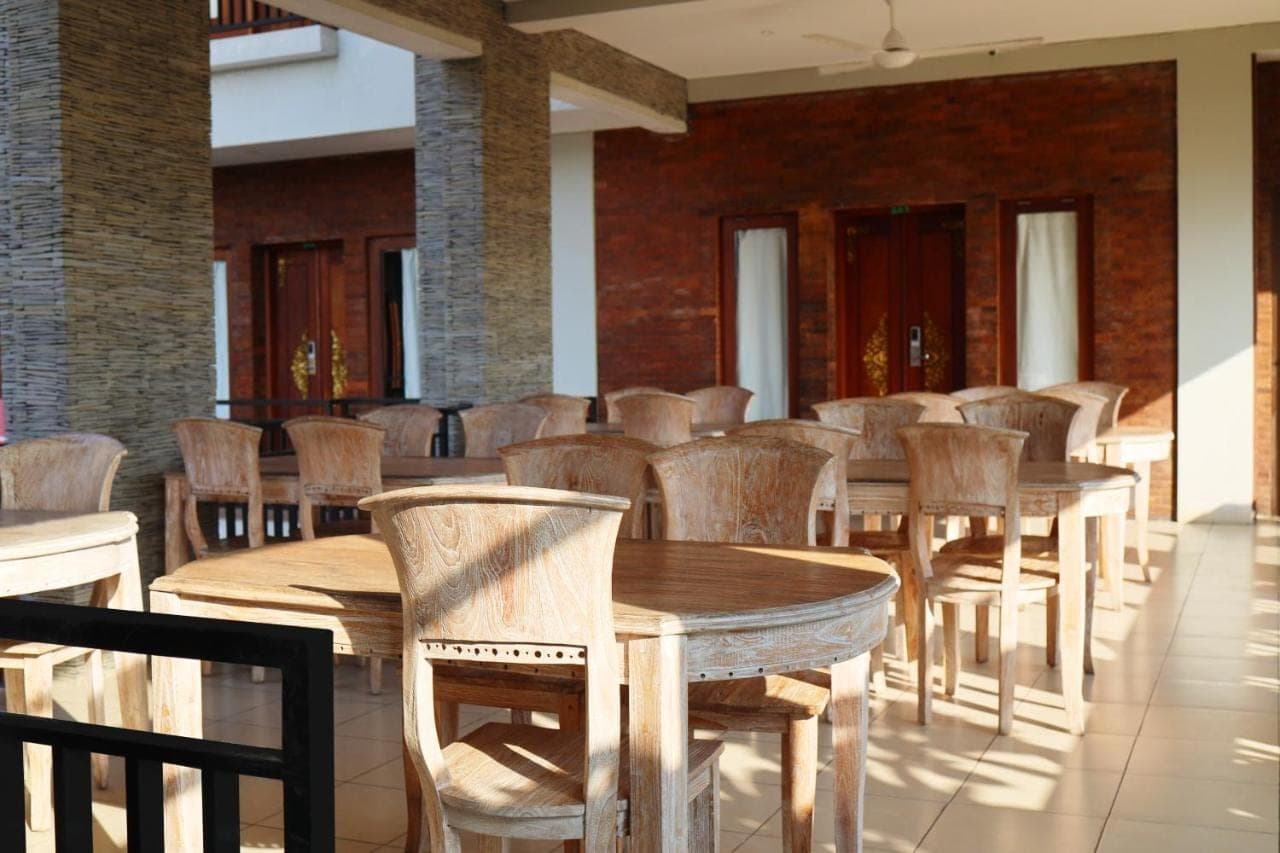 a row of wooden tables and chairs in a room at Gelatik Bed And Breakfast in Seminyak