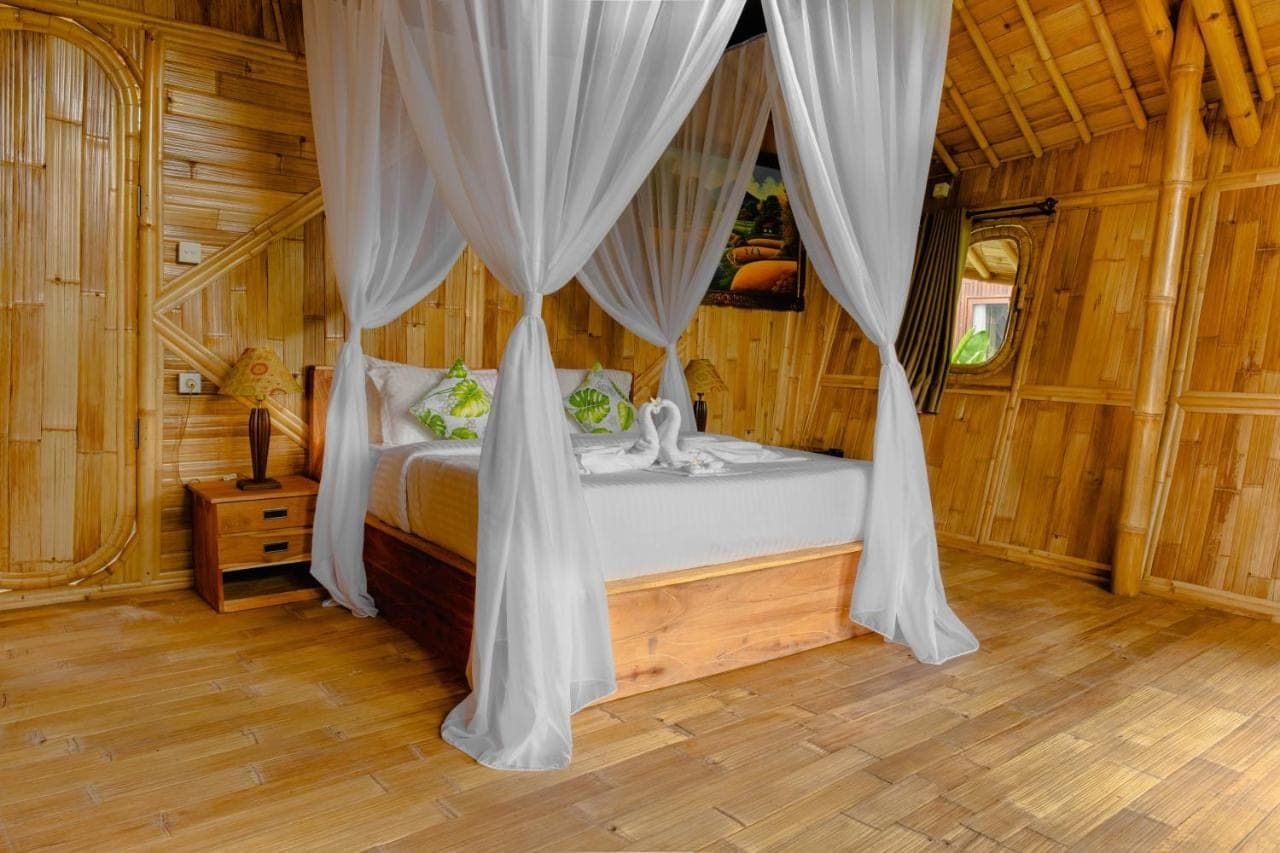 a bedroom with a bed with curtains in a room at Aura Cendana Hill Sidemen by AGATA in Sidemen