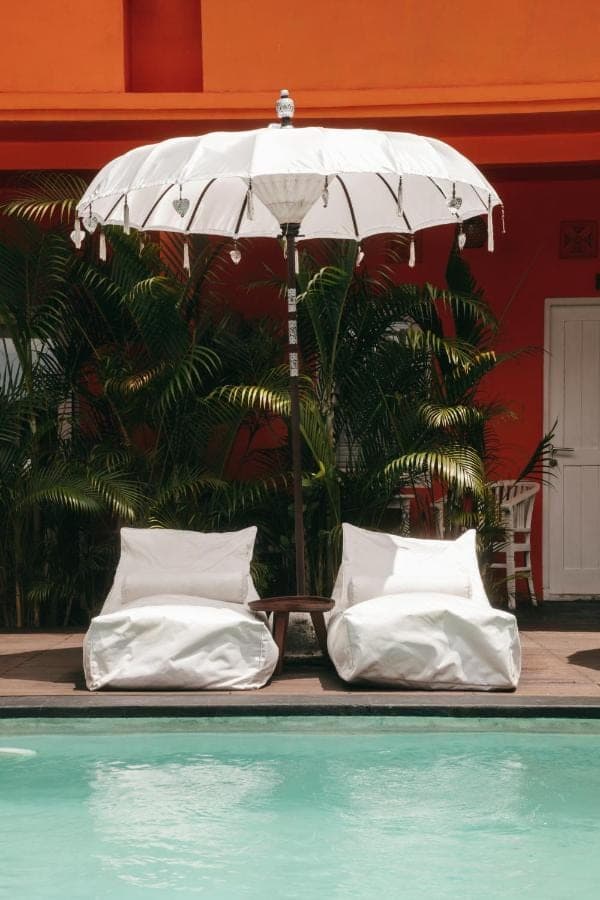 two white pillows sitting under an umbrella next to a pool at The Room Padang-Padang in Uluwatu