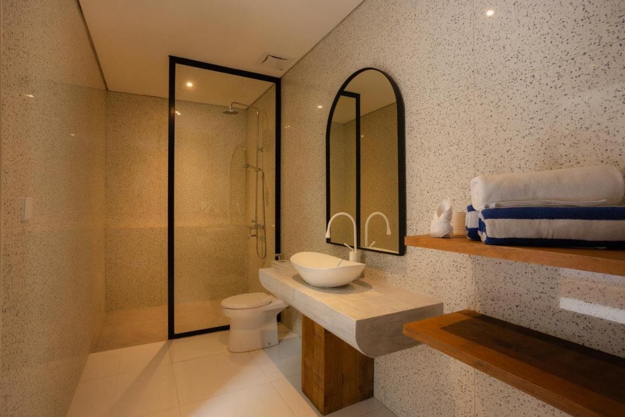 a bathroom with a sink and a toilet and a mirror at Villa Batu Putih 2 Seminyak - BEHIND LA FAVELA in Seminyak