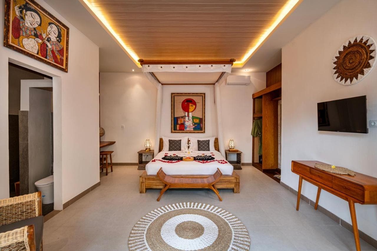 a bedroom with a bed and a flat screen tv at Kubu Rama Ubud Cottage in Ubud