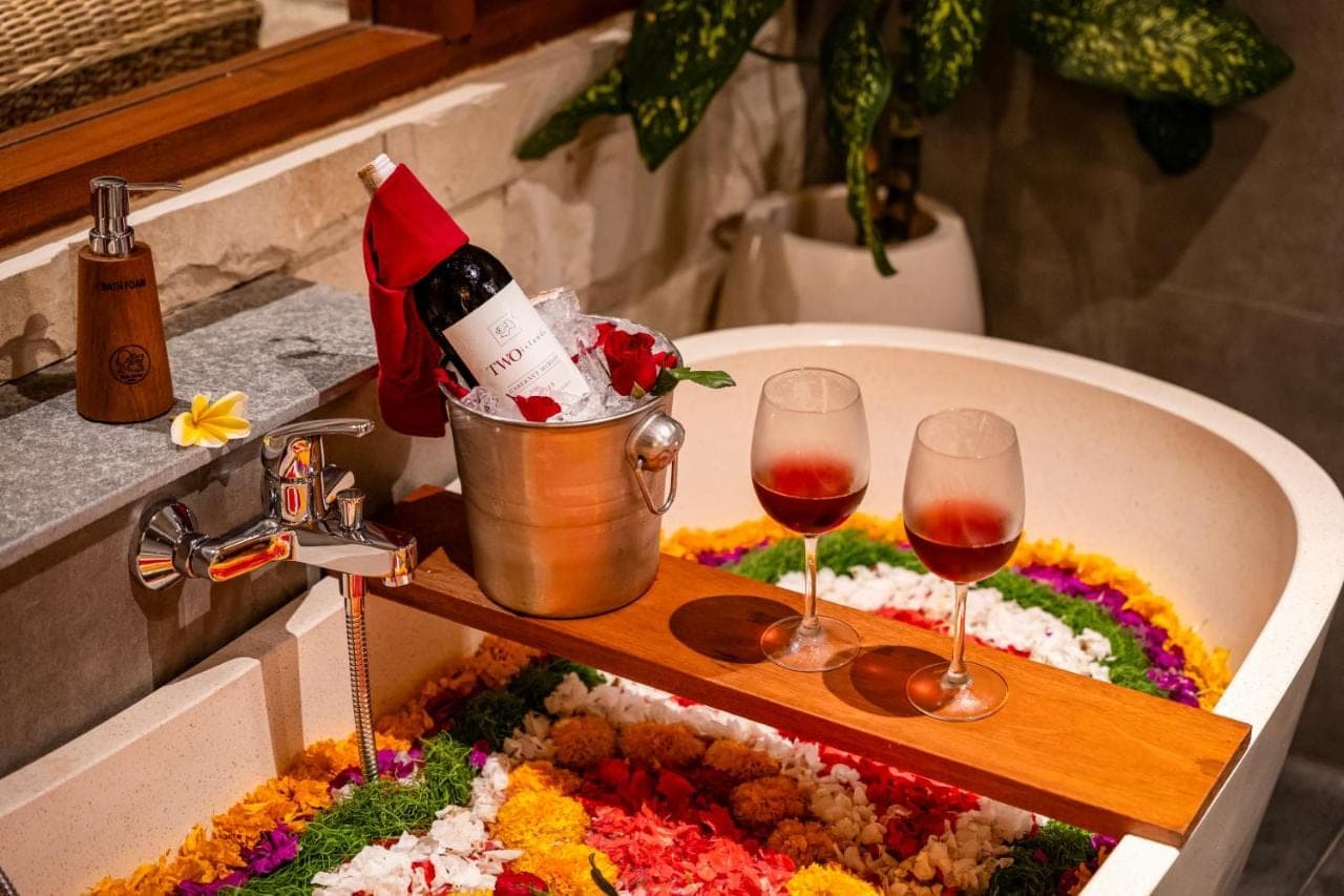 a sink with a bottle of wine and two wine glasses at Kubu Rama Ubud Cottage in Ubud