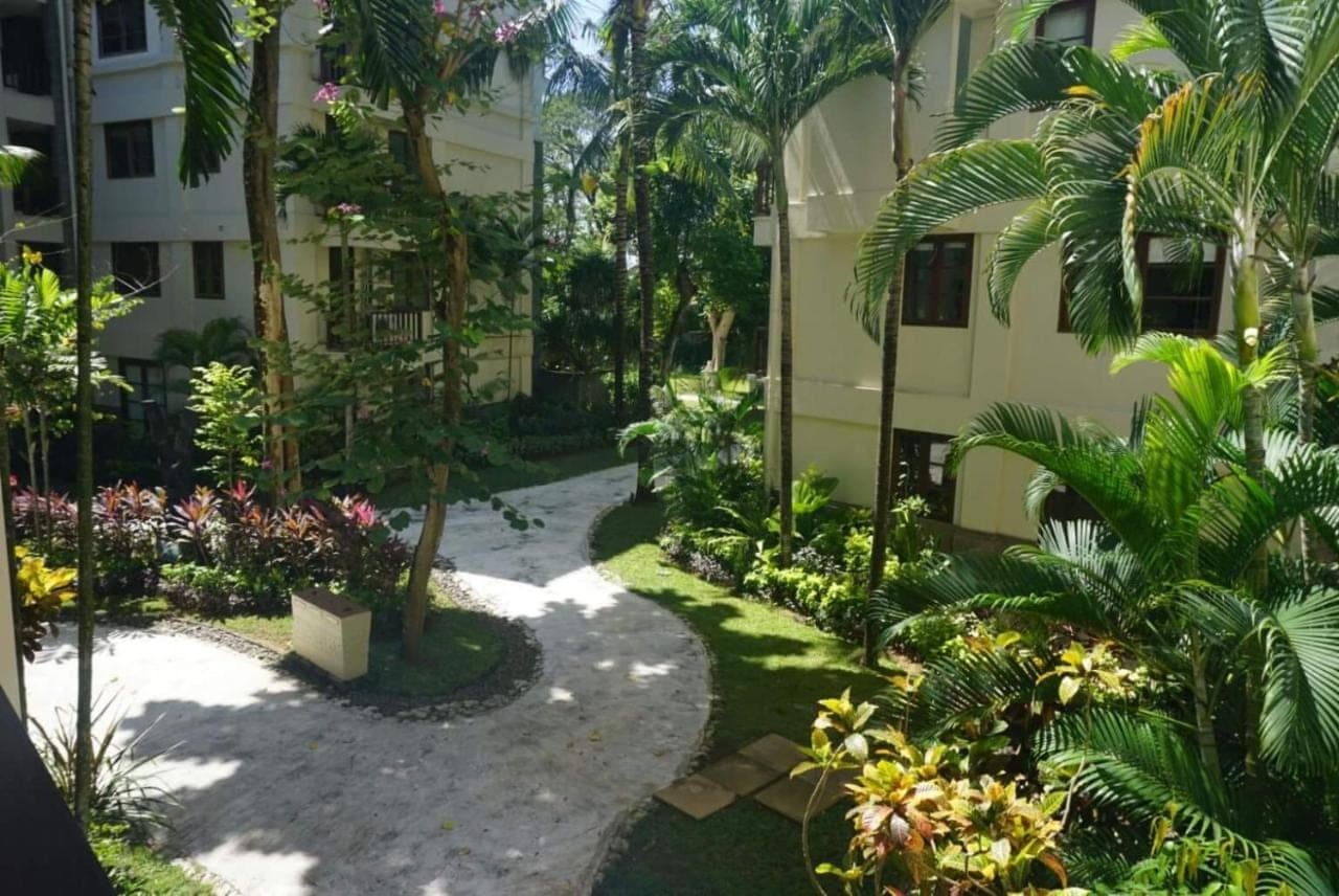 a courtyard of a building with trees and flowers at Ruby Nusa Dua Bali in Nusa Dua