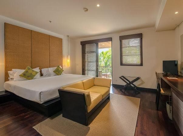 a bedroom with a bed and a couch and a television at Ruby Nusa Dua Bali in Nusa Dua