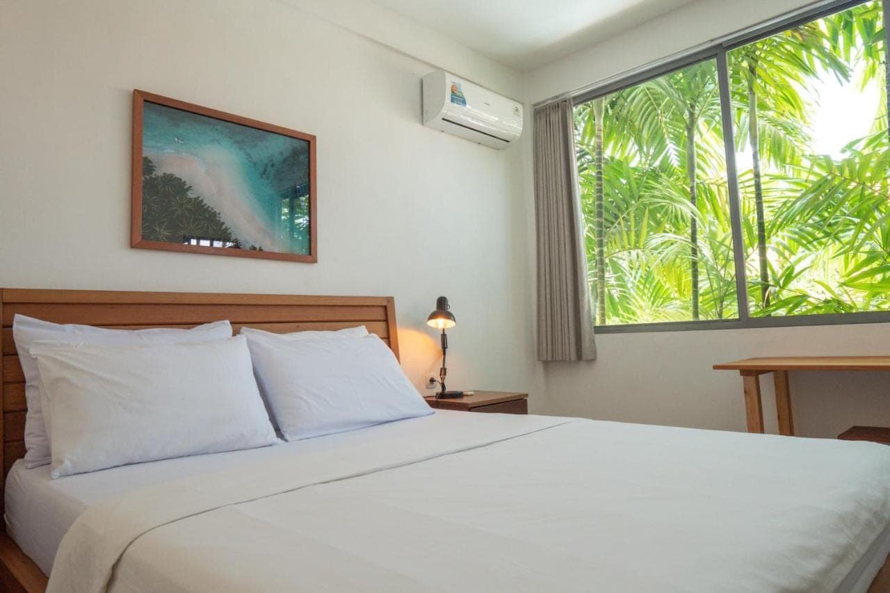 a bedroom with a white bed with a large window at 007 Surfhouse Bali in Uluwatu