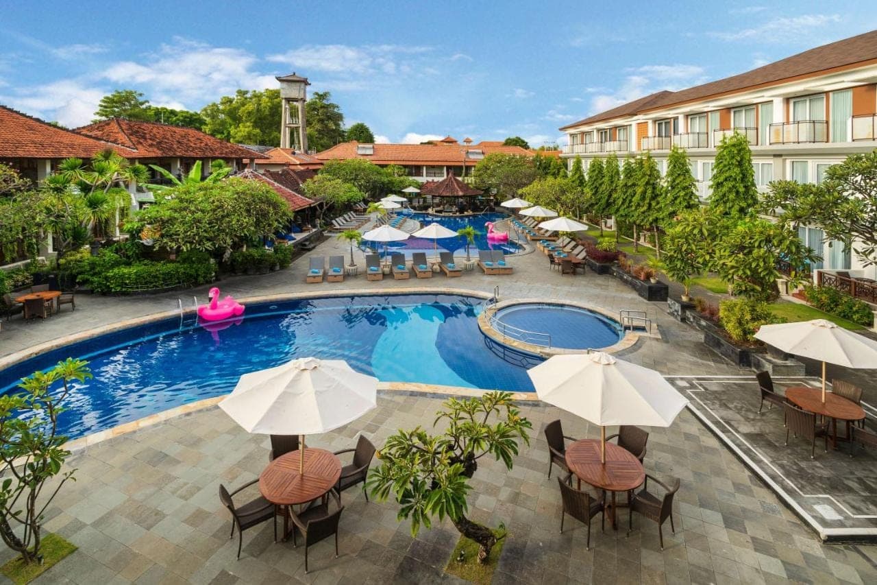 an overhead view of a resort pool with tables and umbrellas at Kuta Beach Club Hotel in Kuta