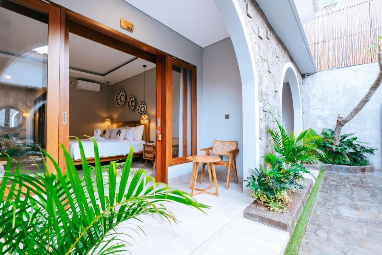 a bedroom in a villa with a bed and some plants at Villa Koura Kuta - 6 Min to Airport Ngurah Rai in Kuta